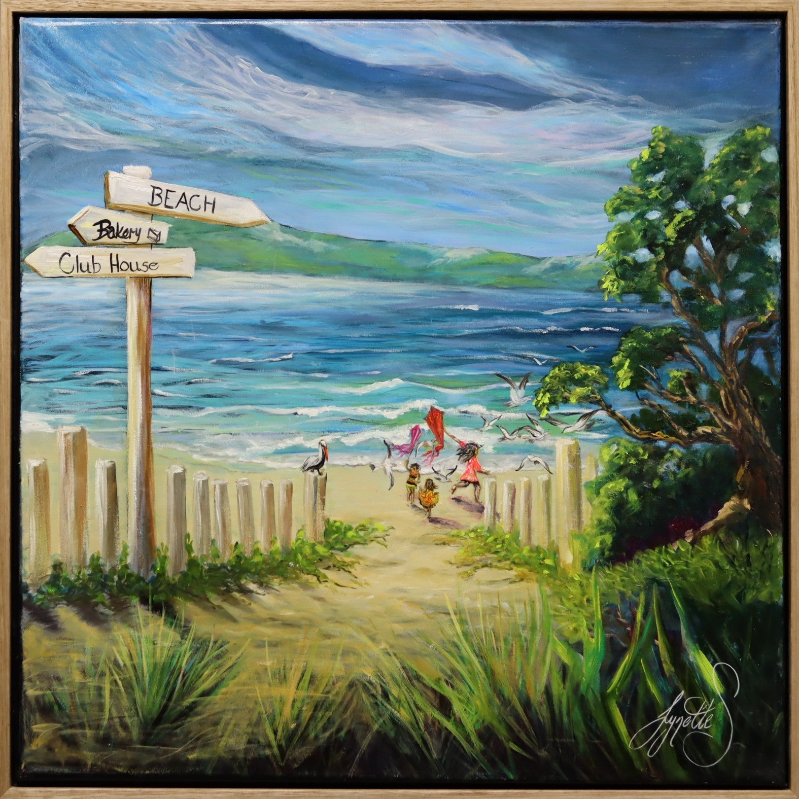 Coastal beach painting showing children running along a sandy path toward the ocean flying colourful kites, with blue sea, sky and coastal greenery in a joyful Australian seaside artwork by Lynette Mary Skeers
